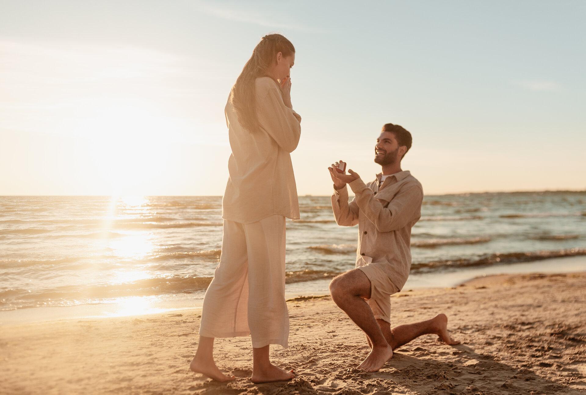 man with ring making proposal to woman on beach